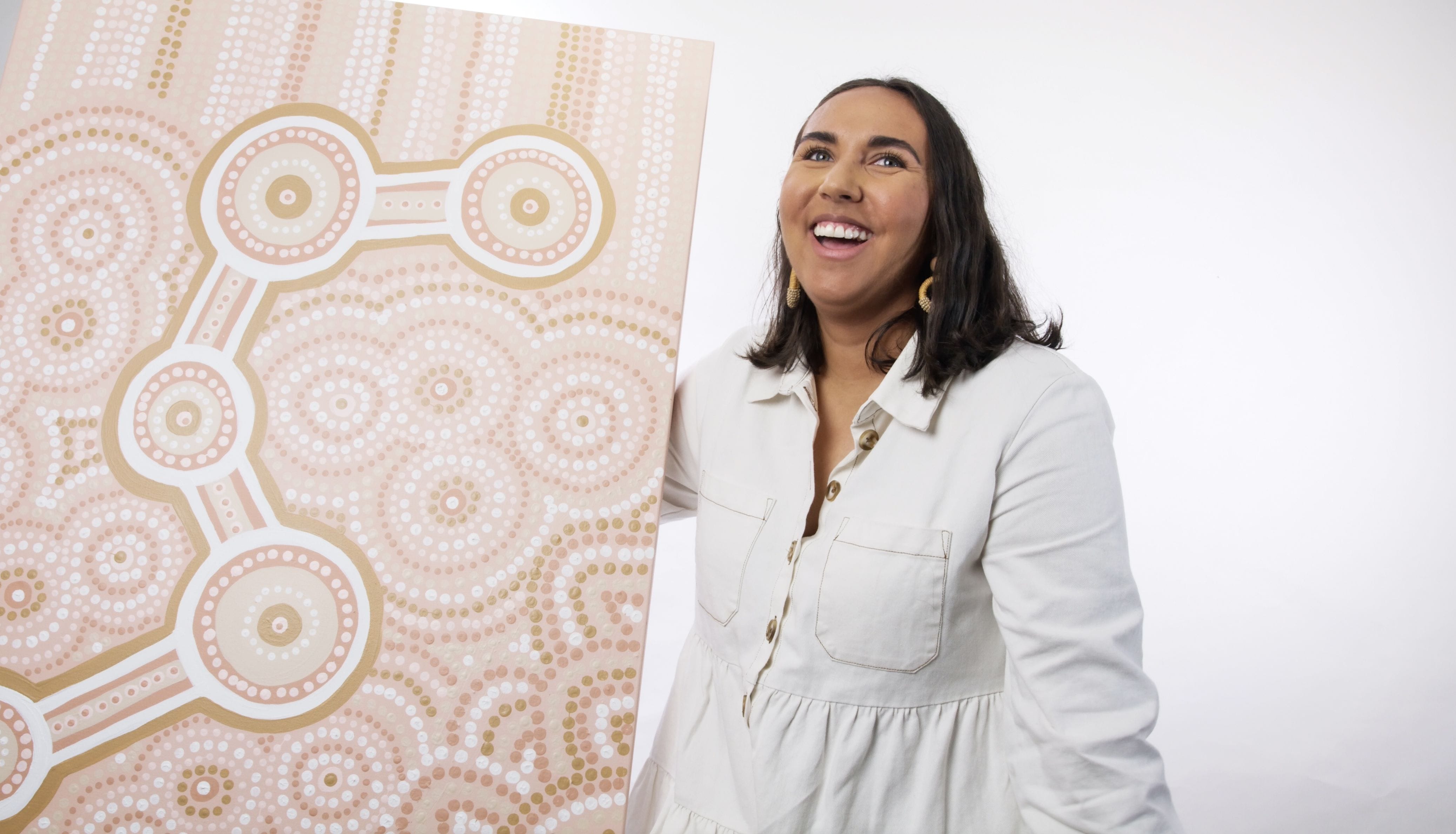 Gold Coast artist and proud Wiradjuri woman Katrina Graves poses with her art
