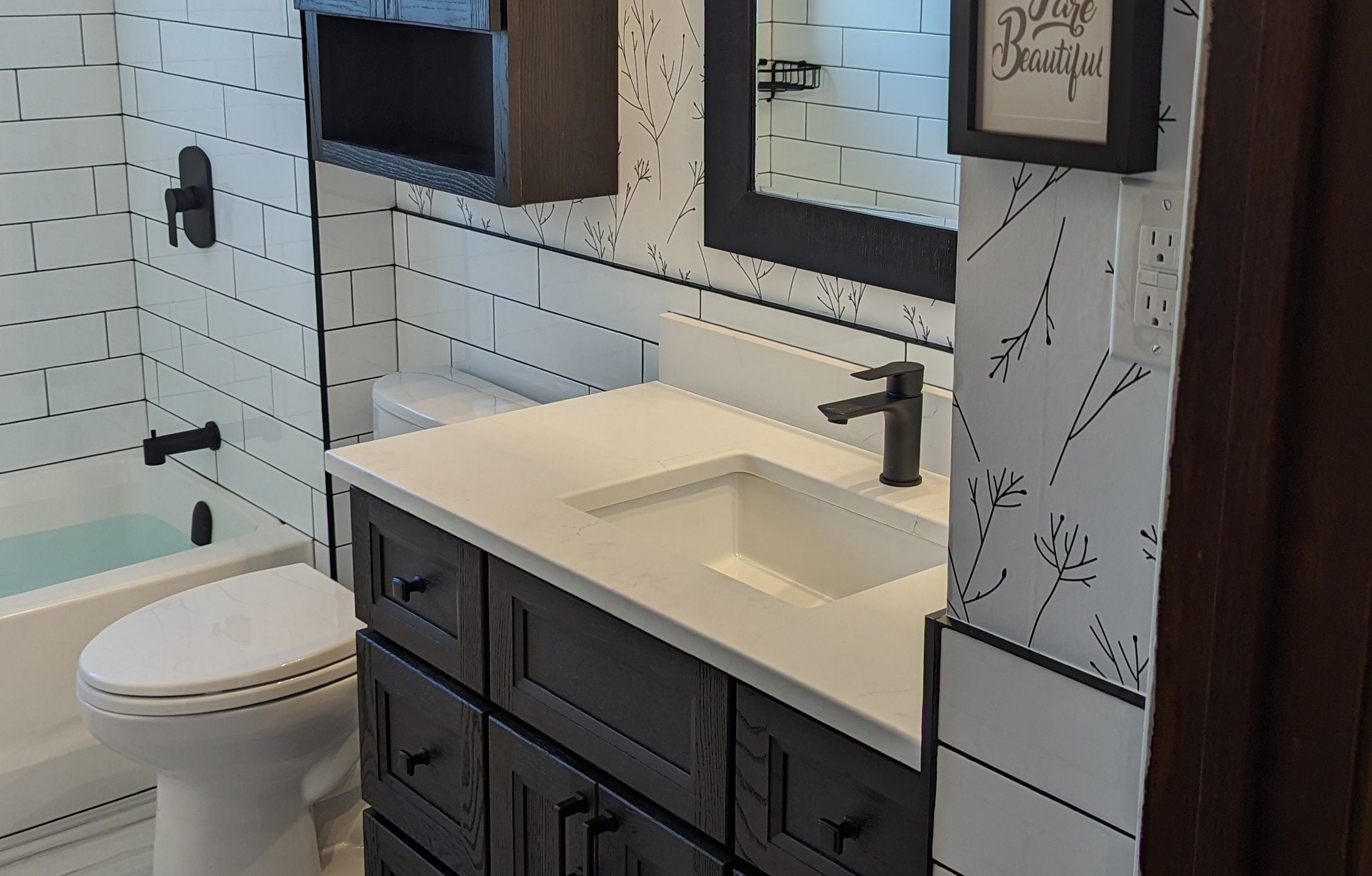 Newly renovated bathroom in darker tones for the cabinet and white for the accessories -  leveraging wall mounted storage to make the most of the space