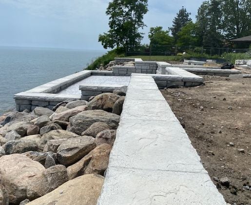 23 m&egrave;tre concrete footings,3500 lbs redi-rock blocks, hosting a patio_terrace followed by another wall stepping into the backyard,  wave protected by 15 truckloads of boulders