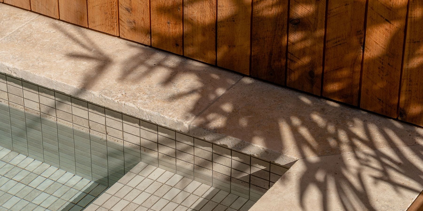 Natural stone tiling in a pool to help create a sense of a wellness retreat