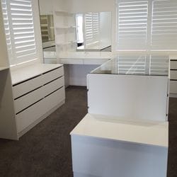 WIR using White HMR Melamine, centre island with 6mm toughened clear glass top. No backing. Open drawer fronts and white 32mm diameter hanging rail. Built in makeup station with floating shelves & mirror