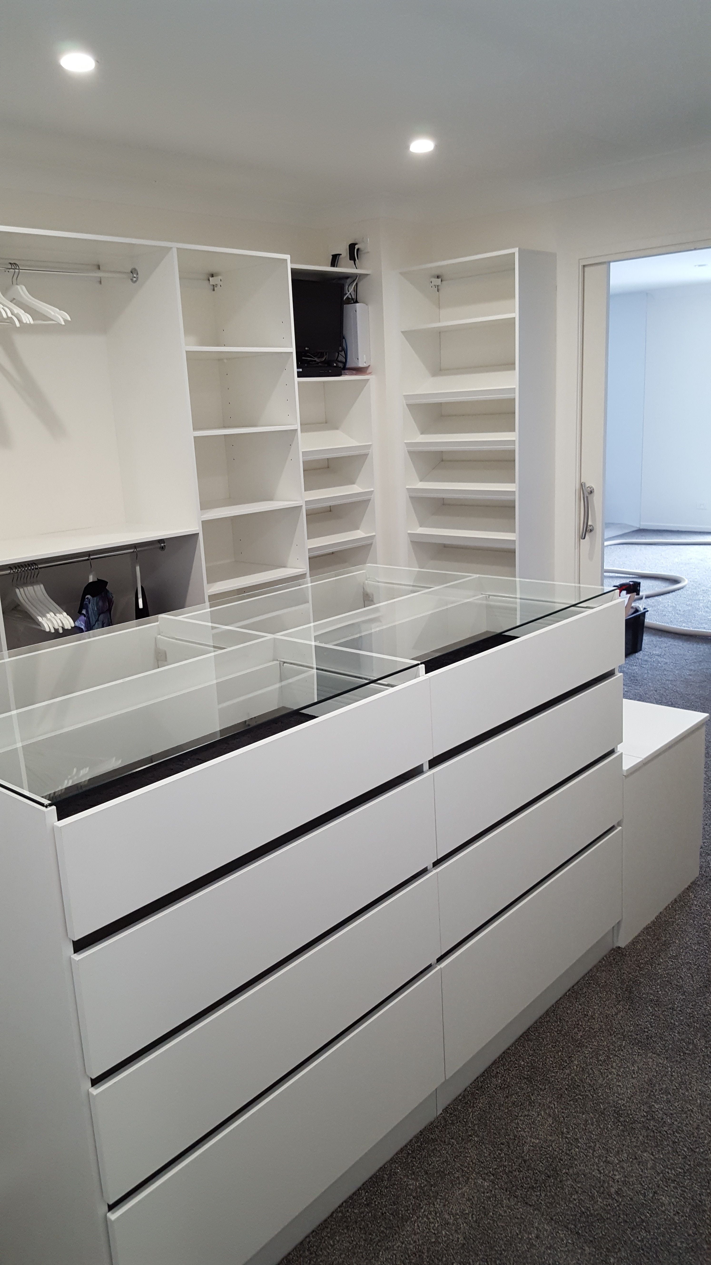 WIR using White HMR Melamine, centre island with 6mm toughened clear glass top. No backing. Open drawer fronts and white 32mm diameter hanging rail. Sloping shoe racks with upstands