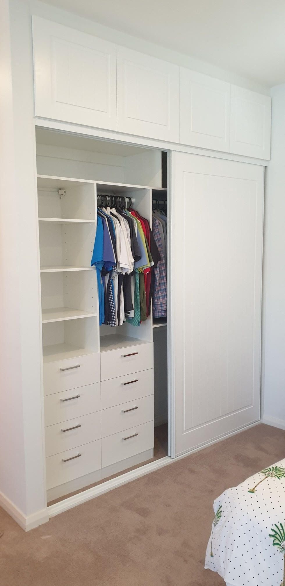 BIR using White HMR Melamine with drawers and shelving behind sliding doors. Above wardrobe storage with profiled hinged doors