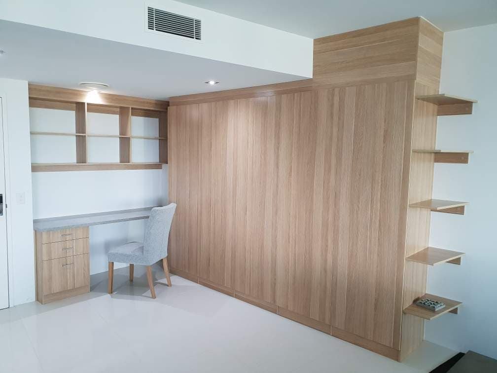 Study & storage for Q1 apartment. Desk top using Flexipanels "Concrete",cabinets using Polytec "Natural Oak Matt". Angled shelving to suit tiled floor, bulkhead to suit ceiling line.