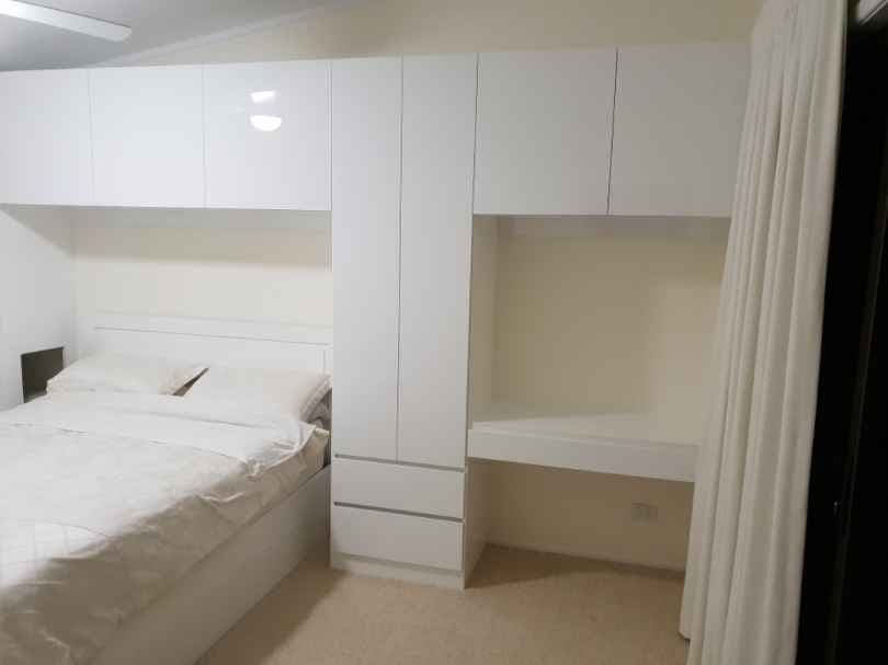 Surround Bed storage with desk top using Polytec "Ultra White Createc". Cut outs in side panels for owners respiratory equipment - all custom made to suit. Hinged doors with Blum push catch openers and hinges