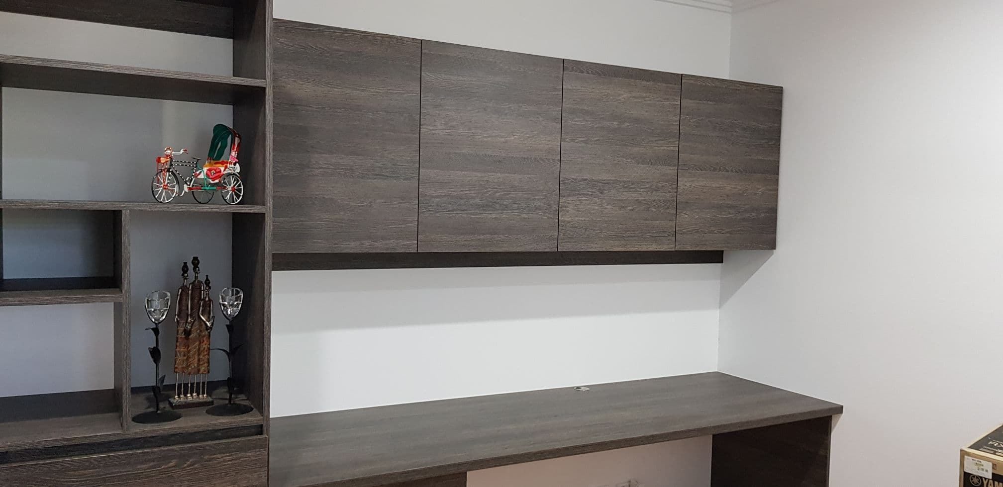 Study with side display shelving. 33mm post form desk top.Overhead hinged doors. Using Polytec "Belgian Oak Matt"