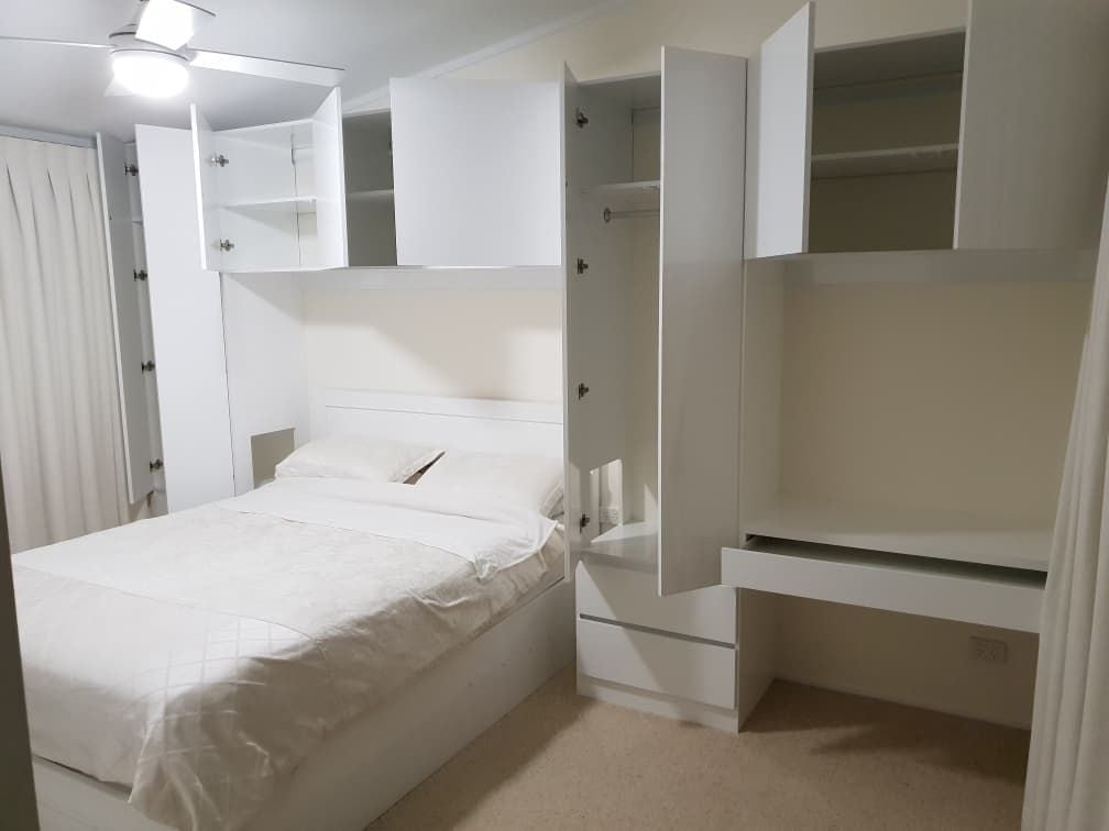 Surround Bed storage with desk top using Polytec "Ultra White Createc". Cut outs in side panels for owners respiratory equipment - all custom made to suit. Hinged doors with Blum push catch openers and hinges