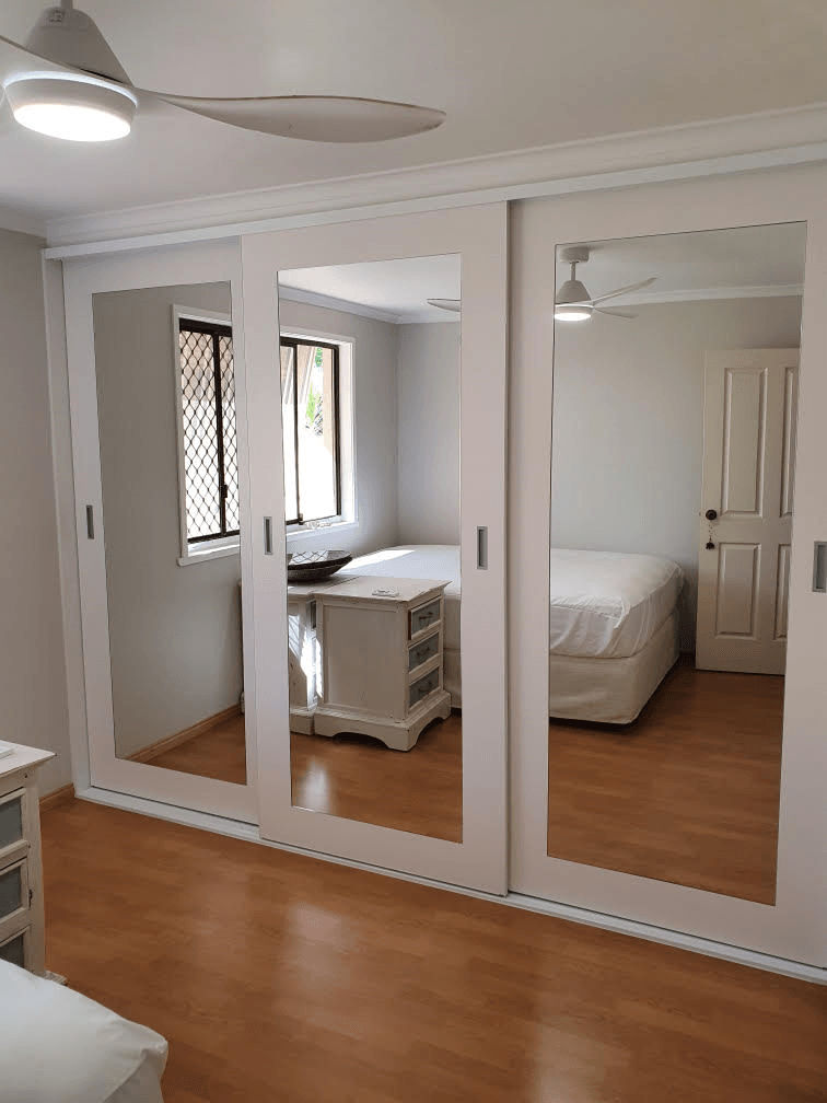 Frame less sliding doors with 150mm 2 pack painted border & mirror glass inserts. Satin Silver recessed handles. Dias White top & bottom tracks