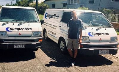 BumperTech technician standing in front of two mobile car bumper repair vans