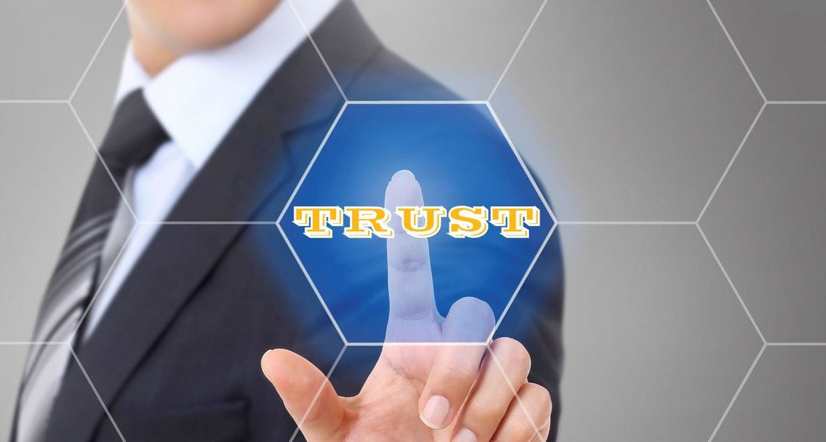 It's critical to establish credibility and trust - a good website can help - image of man touching digital screen and lighting up the word TRUST