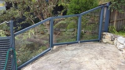 Custom timber frame fence built over sloped rockery, with clear polycarbonate infills