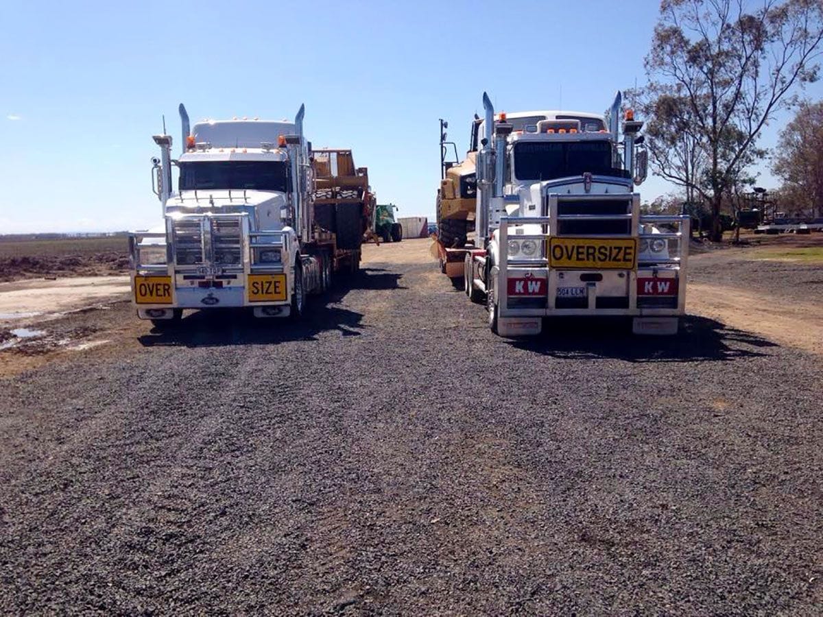 Two trucks loaded with heavy earthmoving equipment