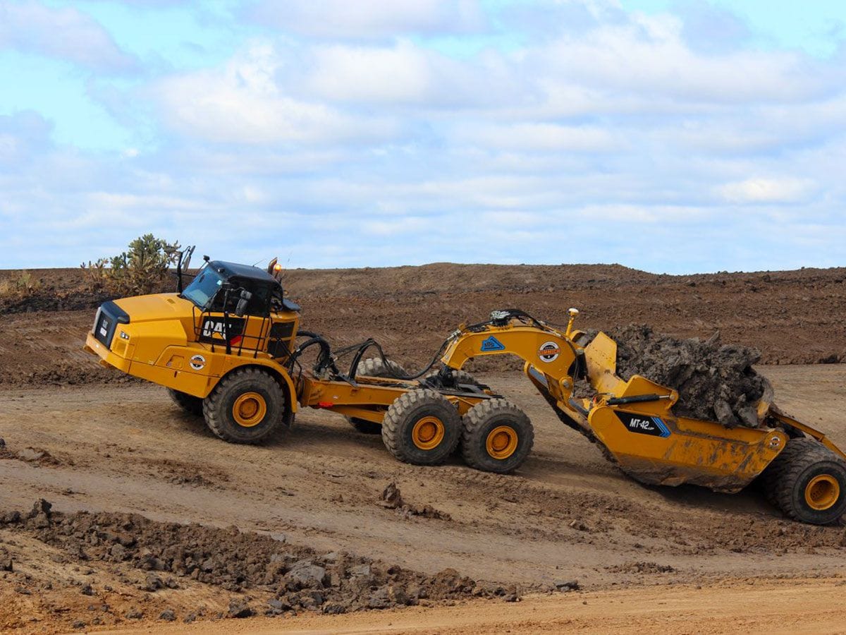 Earthmoving equipment removing gravel fill from a site.