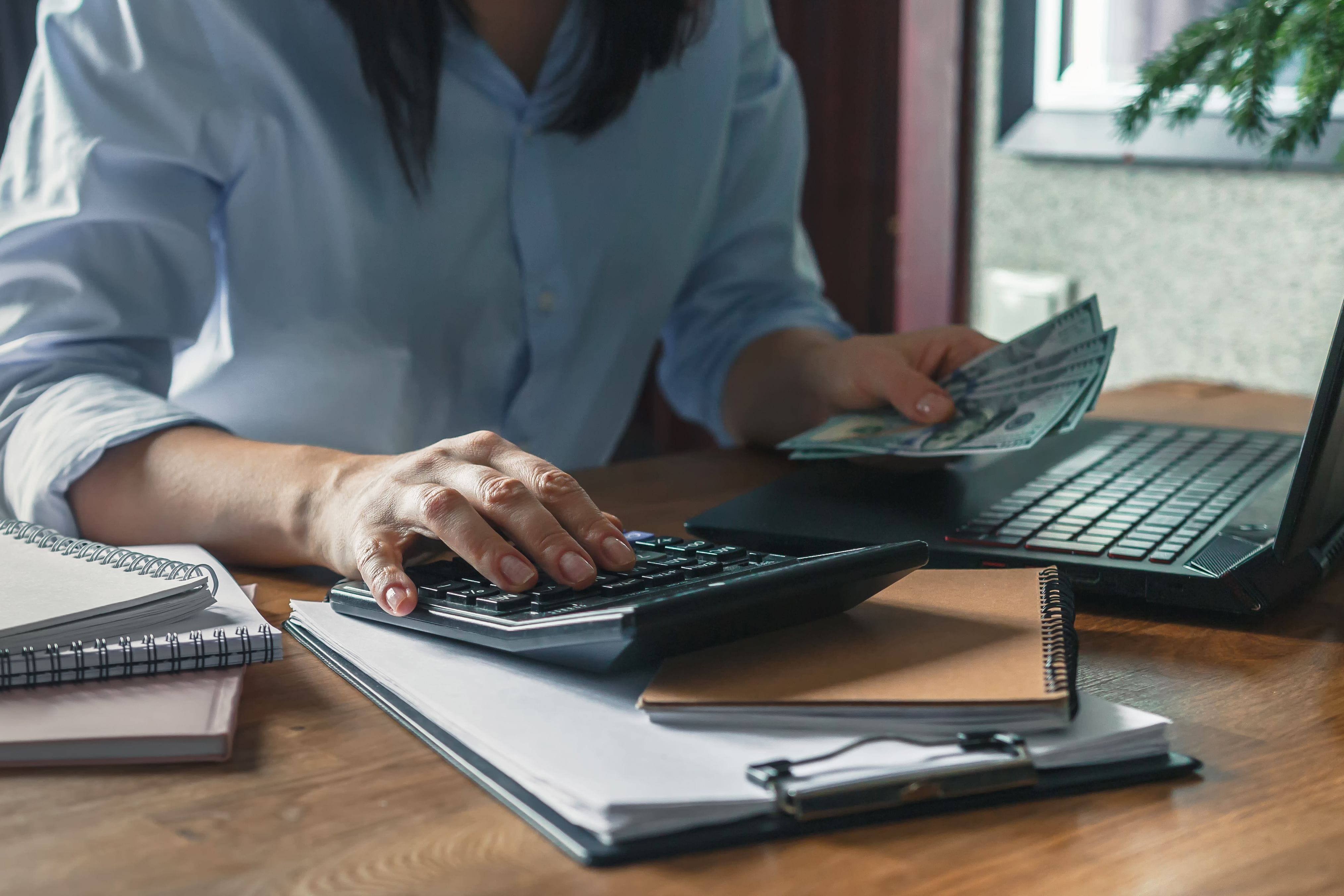 man holding money works on his calculator to determine a budget with rising inflation at home