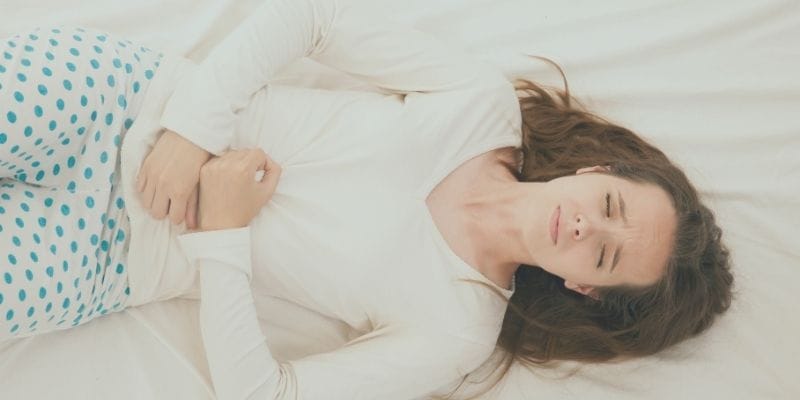Woman showing signs of hormonal imbalance in the form of PMS cramping