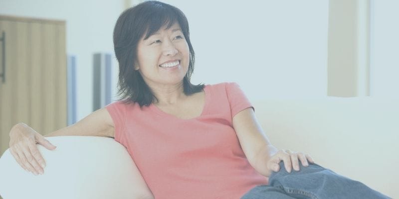 50 year old woman smiling while resting on a couch 