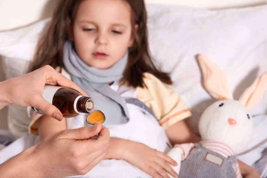 A little girl is getting compounded flavour medicine from a bottle.