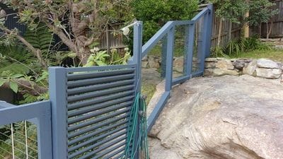Custom timber frame fence built over sloped rockery, with clear polycarbonate infills