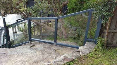Custom timber frame fence built over sloped rockery, with clear polycarbonate infills