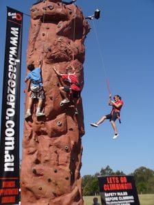 Kids using the climbing wall and abseiling down on an automatic belay system.